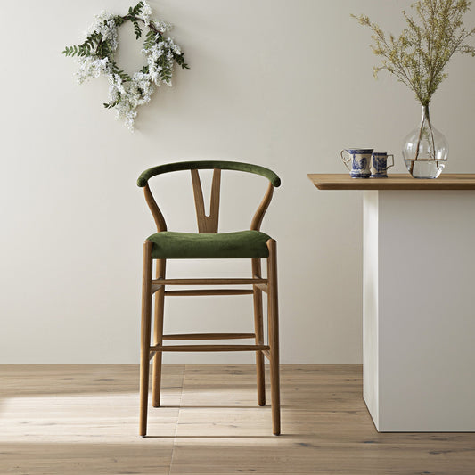 Tabouret de bar rembourré Hansel Wishbone, velours vert mousse et cadre en noyer clair