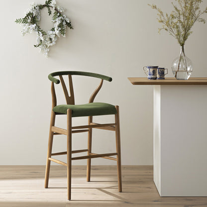 Tabouret de bar rembourré Hansel Wishbone, velours vert mousse et cadre en noyer clair