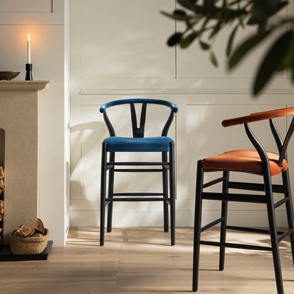 Tabouret de bar rembourré Hansel Wishbone, velours bleu et cadre noir